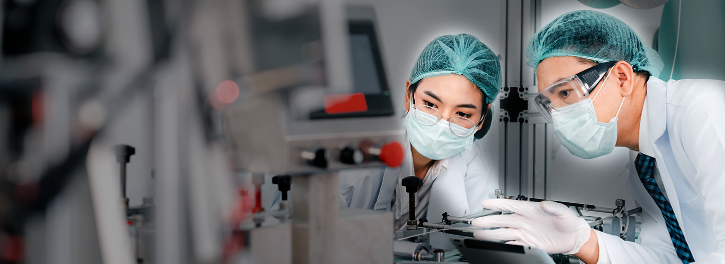 Both male and female Asian scientists are outfitted with protective gear. Examining the factory's machinery and materials used in the mask-making process. Covid 19 is a piece of preventive equipment